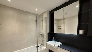 Une salle de bain moderne avec une douche à parois de verre, un lavabo blanc et un grand miroir.