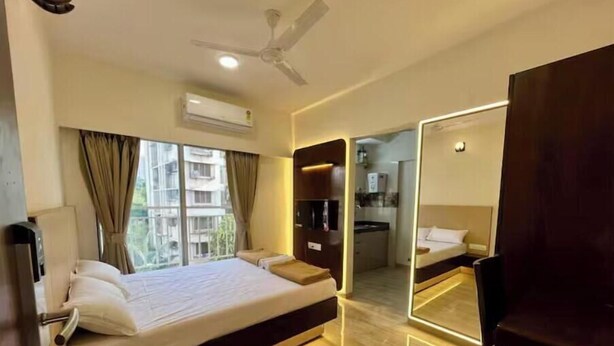 A hotel room with a large bed, a ceiling fan, an air conditioning unit, and a view of the outside.