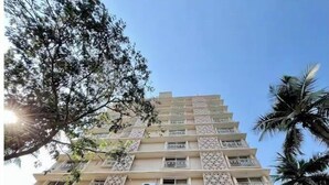A multi-story building with balconies, large windows, and decorative lattice patterns. - Executive 1BHK Suite | Near Link Road (Mumbai)