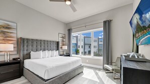 Moderni hotellihuone, jossa on suuri sänky, työpöytä ja ikkunasta avautuva näkymä ympäröiviin rakennuksiin.