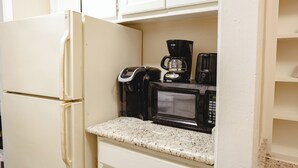 Cocina compacta equipada con refrigerador, microondas, cafetera y tostadora.