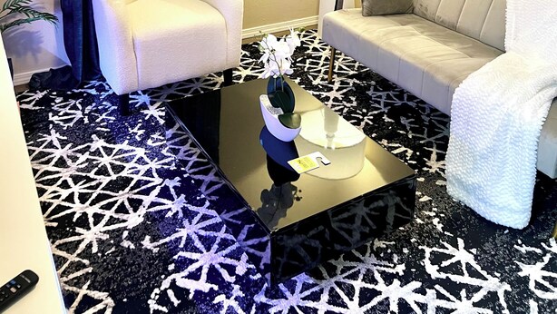 Una sala de estar moderna con un sofá, un sillón y una mesa de centro con un jarrón decorativo.