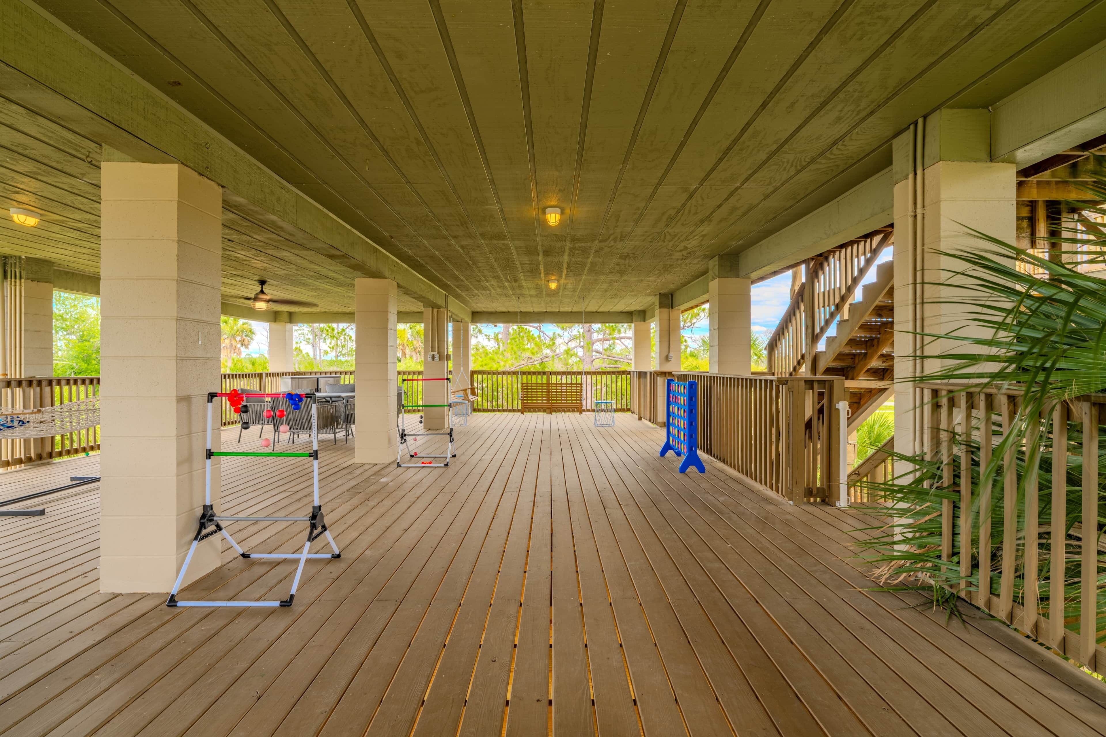 Un espacio al aire libre cubierto con terraza de madera, columnas y vistas a un edificio con escaleras.