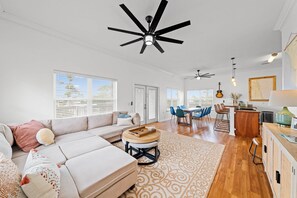 A spacious living area with a large sofa, a dining table, and a kitchen area.