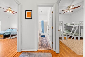 A room with a bed, a ceiling fan, a framed picture, and a bathroom in the background.