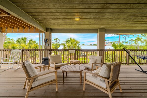 A covered outdoor seating area with wooden furniture and a view of the ocean.