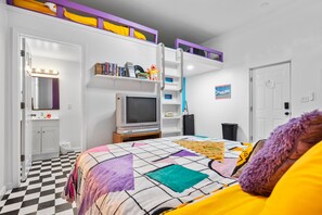 Une chambre à coucher avec un lit, une télévision, une bibliothèque et une porte.
