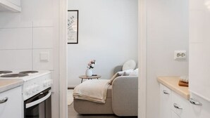 A modern kitchen with white cabinetry, a stove, and a small dining table with a vase of flowers. - Aurora City Studio By Lapland Host (Rovaniemi)