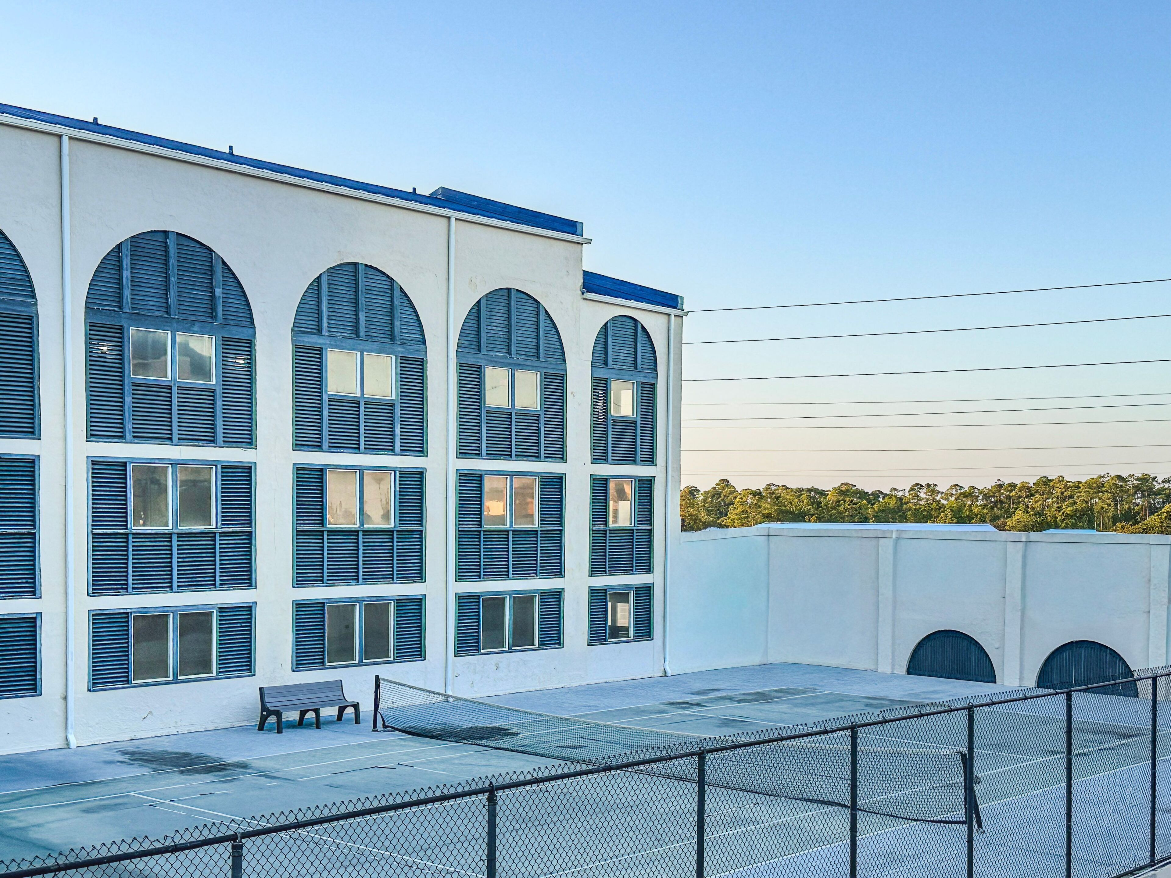 Un edificio con varias ventanas arqueadas y una cancha de tenis.