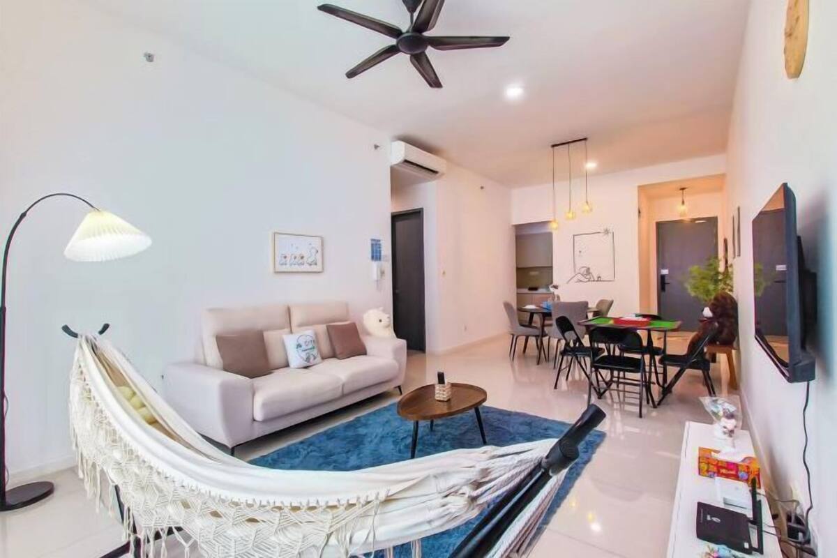 A modern living room with a sofa, a hammock, a dining area, and a TV.
