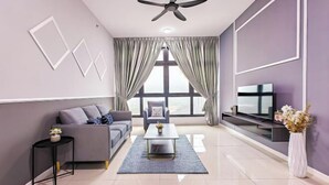 A modern living room with a grey sofa, a coffee table, a TV on a stand, and a ceiling fan.