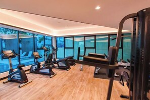 Un gimnasio moderno con equipamiento de ejercicio, ventanas amplias y suelo de madera.