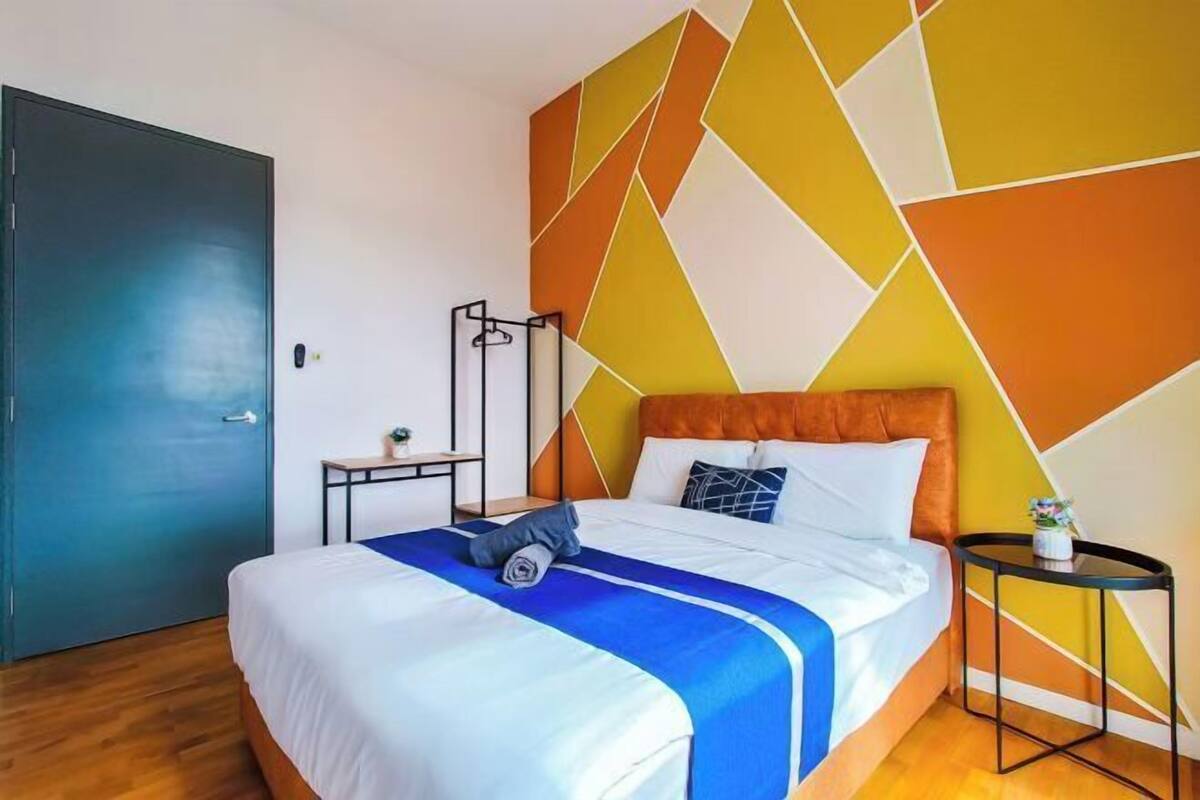 A hotel room with a bed, a bedside table, a wall with geometric patterns, and a door.