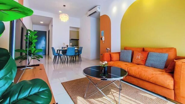 A modern living room with a sofa, a dining table, chairs, and a large plant.