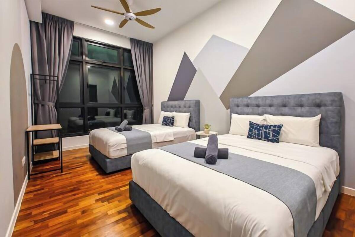 A modern hotel room with two beds, a wooden floor, a ceiling fan, and a large window with curtains.