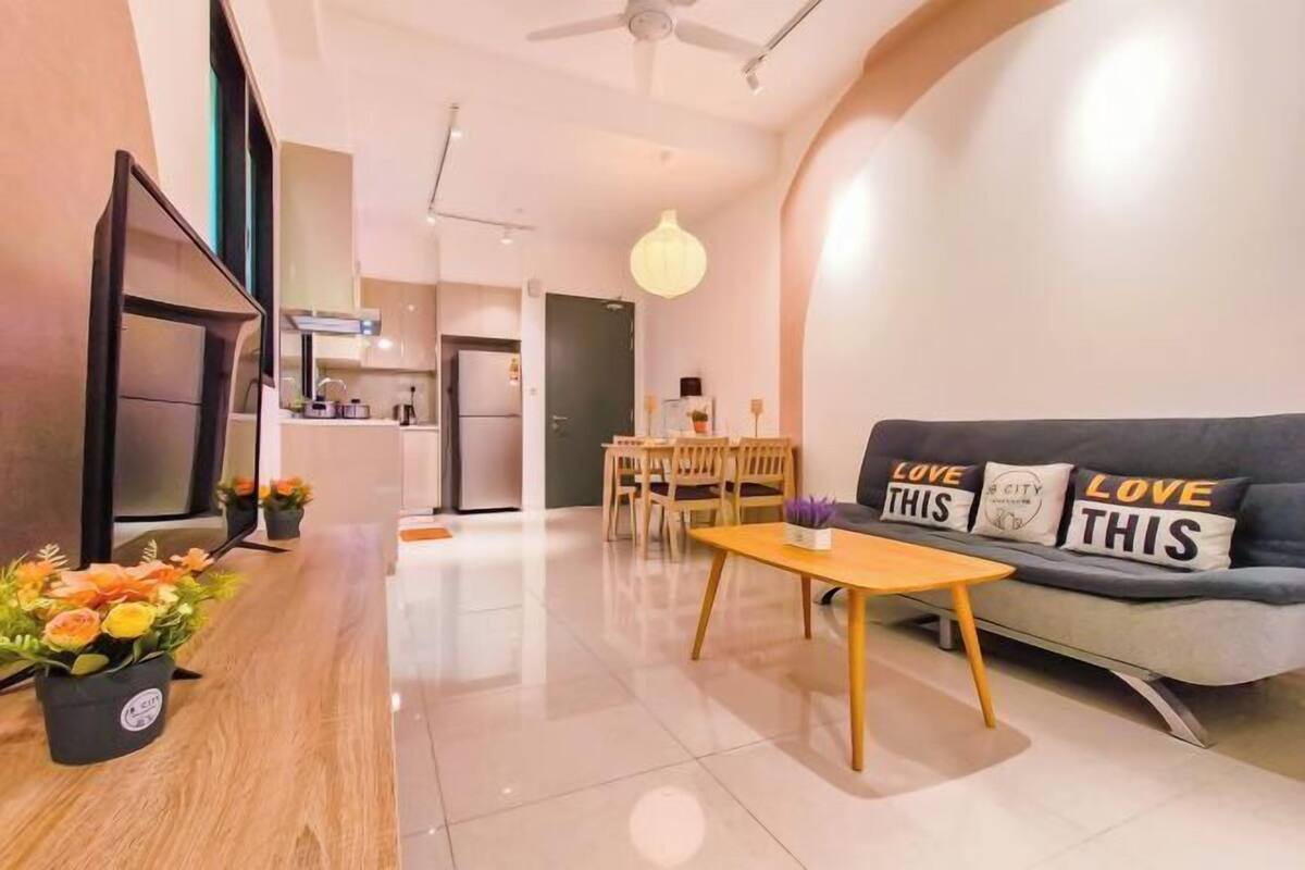 A modern living room with a sofa, a dining table, and a kitchen in the background.