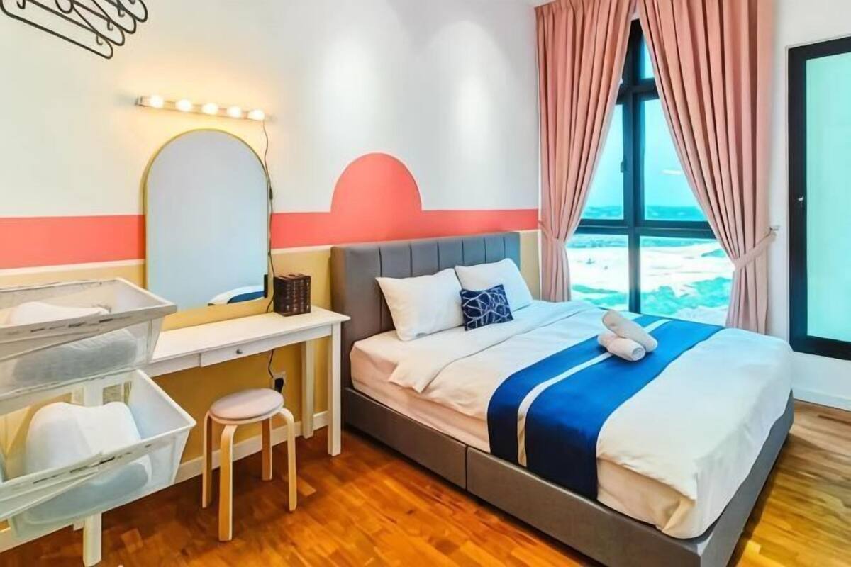 A bedroom with a bed, bedside table, chair, and a window with curtains.