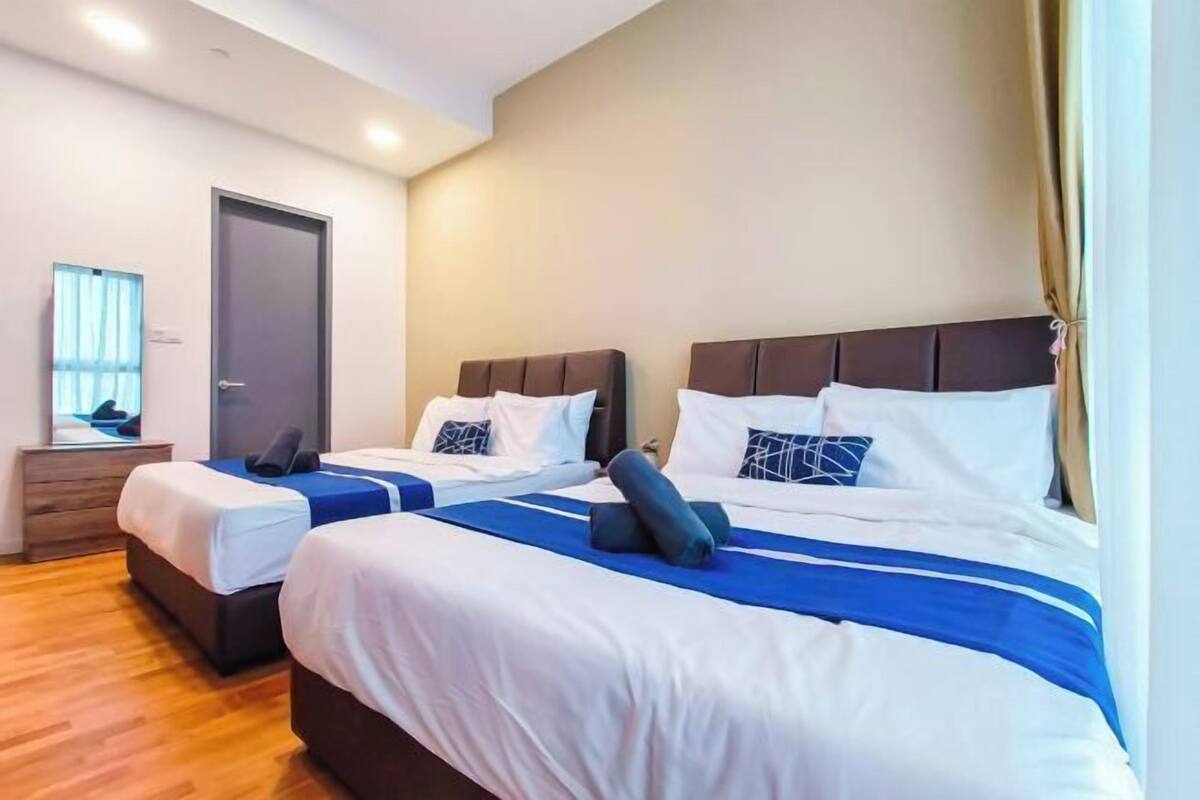 A hotel room with two beds, a wooden dresser, a television, and a door.