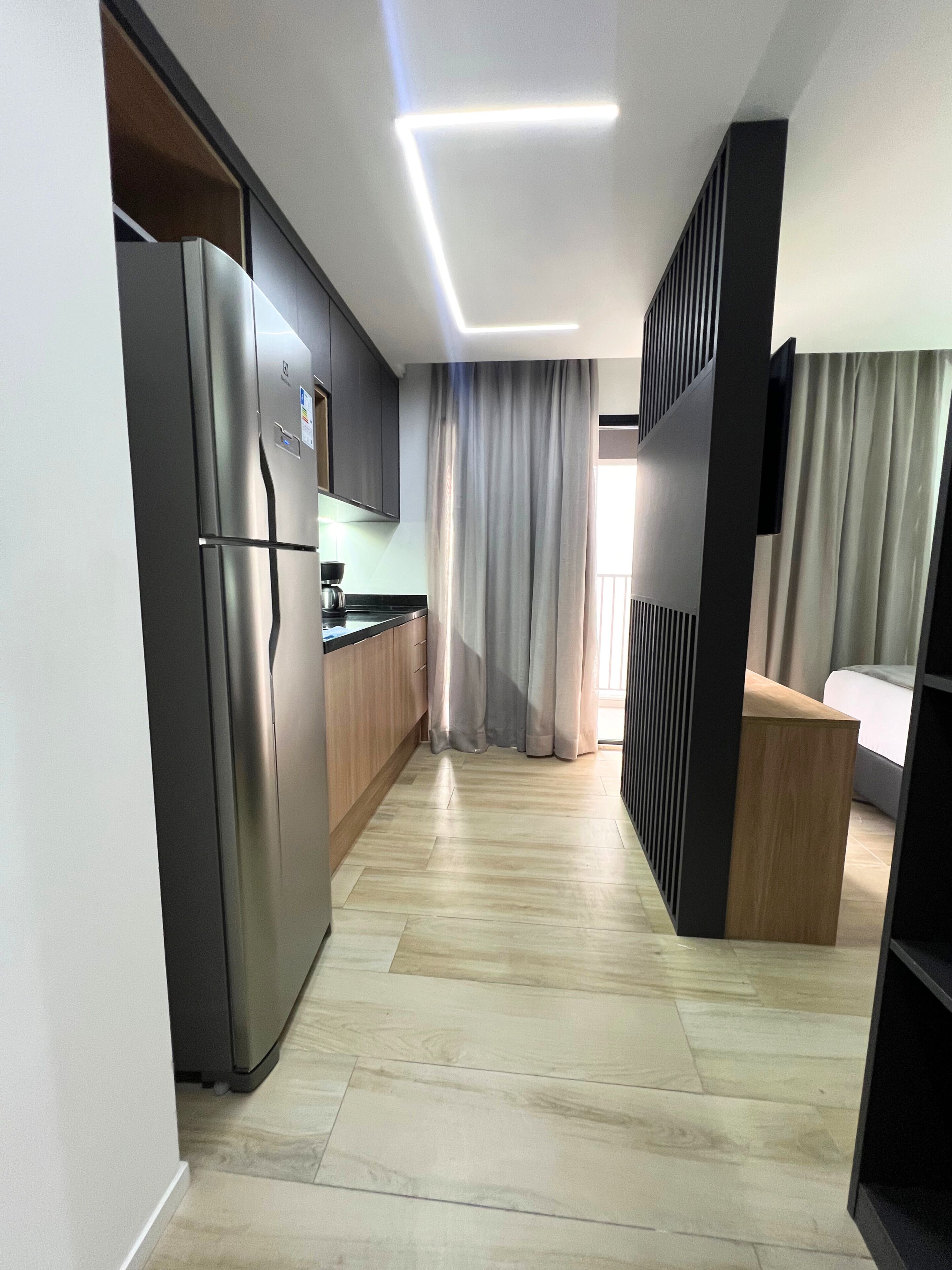 A modern kitchen with a refrigerator, wooden cabinets, and a built-in oven.