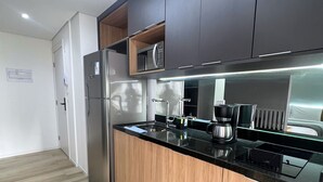 Eine moderne Küche mit Holzschränken, einem Edelstahlkühlschrank, einer eingebauten Mikrowelle und einer schwarzen Arbeitsplatte.