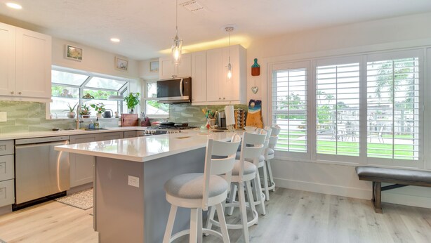 A modern kitchen with a central island, bar stools, and large windows. - Waterfront Largo Home w/ Canal Access + Boat Dock (Largo)