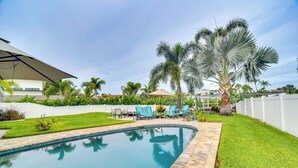 A swimming pool with a tiled edge, surrounded by a well-maintained lawn and palm trees. - Waterfront Largo Home w/ Canal Access + Boat Dock (Largo)