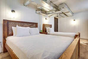 Ein Schlafzimmer mit zwei Betten, Holzkopfteilen und weißer Bettwäsche.