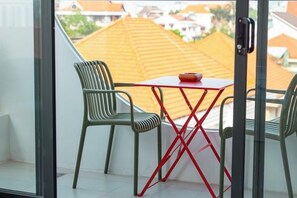 A balcony with two chairs and a small table, overlooking a residential area with orange-roofed houses. - Panda Garden Hotel &Apartment (Ho Chi Minh City)