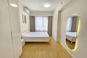A bedroom with a bed, a wardrobe, a mirror, and a window with curtains. - Panda Garden Hotel &Apartment (Ho Chi Minh City)