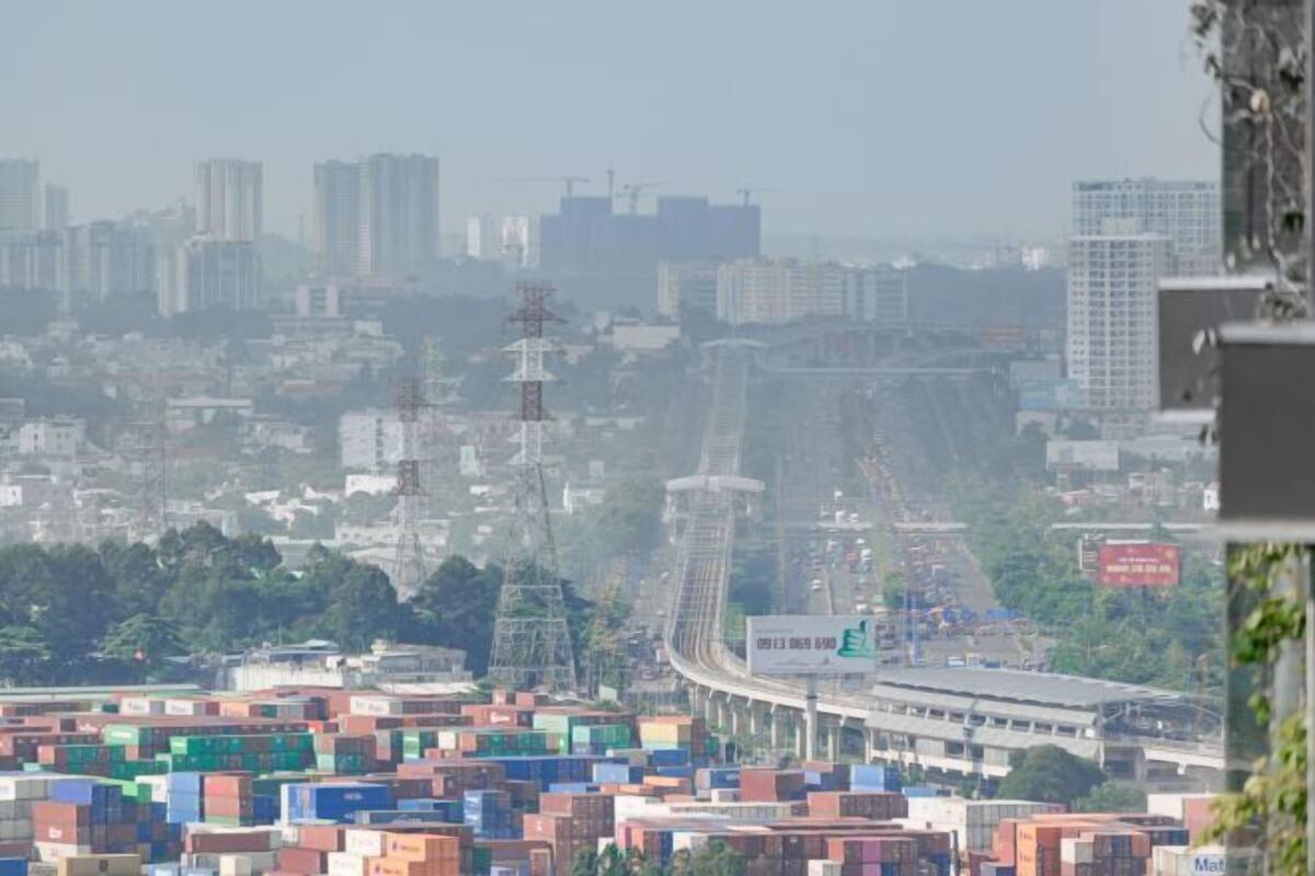 A cityscape with a large number of shipping containers, a highway, and high-rise buildings in the background.