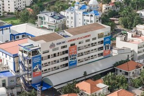 A multi-story building with a prominent American Academy sign, multiple balconies, and a covered walkway. - Panda Garden Hotel &Apartment (Ho Chi Minh City)