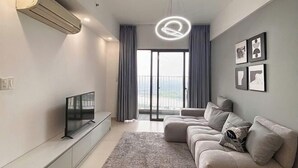 Un soggiorno moderno con una TV a schermo piatto, un divano, un tappeto a motivi e un lampadario.