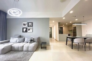 A modern living room with a sectional sofa, a dining table with chairs, and a kitchen in the background. - Panda Garden Hotel &Apartment (Ho Chi Minh City)