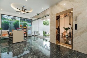 A modern hotel lobby with a reception desk, seating area, and a glass door entrance. - Panda Garden Hotel &Apartment (Ho Chi Minh City)