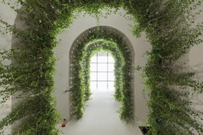 Un espacio interior con un arco de entrada rodeado de abundante follaje verde.