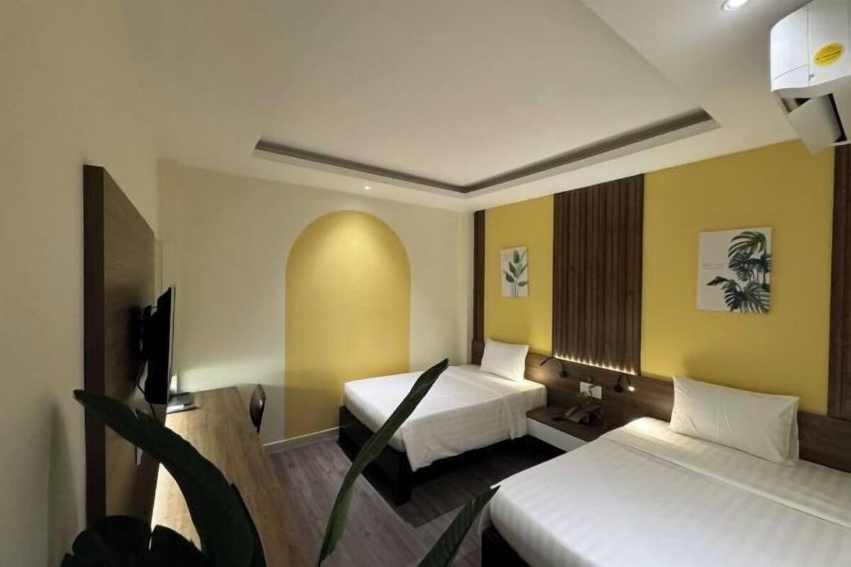 A hotel room with two beds, a flat-screen TV, and a large mirror.