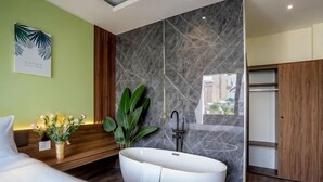 Ein modernes Badezimmer mit einer freistehenden Badewanne, einem Holz-Waschtisch, einem großen Spiegel und Blick auf die Stadt durch ein Fenster.