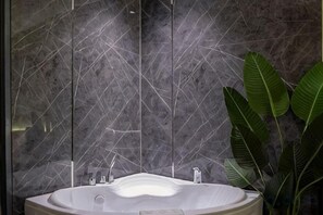A bathroom with a freestanding bathtub, a marble wall, and a potted plant. - La Phan Huy Ich Hotel (Ho Chi Minh City)