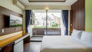 Ein Hotelzimmer mit Bett, Schreibtisch mit Stuhl, einem an der Wand befestigten Fernseher und Blick ins Freie.