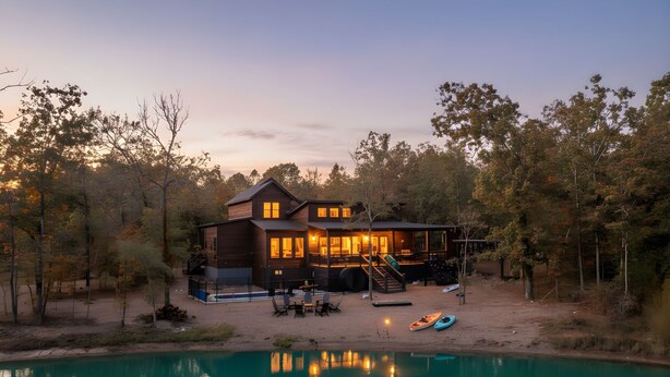 A two-story house with a swimming pool, surrounded by trees and a dock. - Luxury 4BR Cabin on Pond for 18p- Pool, Sauna, Hot Tub & Game Room in Broken Bow (Broken Bow)