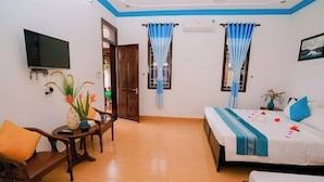 A room with a bed, a TV, a table with a vase, and a chair. - Tra Que Green Villa Hoi An (Hoi An)
