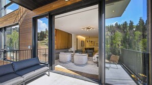 A modern interior with a balcony, large windows, and a view of trees.