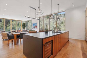 A modern kitchen with a large island, wooden cabinets, and pendant lighting.