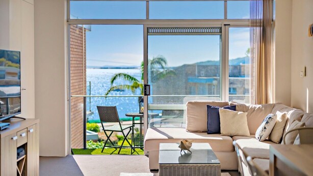A modern living room with a balcony, a sofa, a coffee table, and a TV.