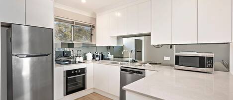A modern kitchen with stainless steel appliances, white cabinetry, and a large island.