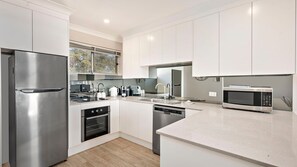 Een moderne keuken met roestvrijstalen apparatuur, witte kastjes en een groot eiland.