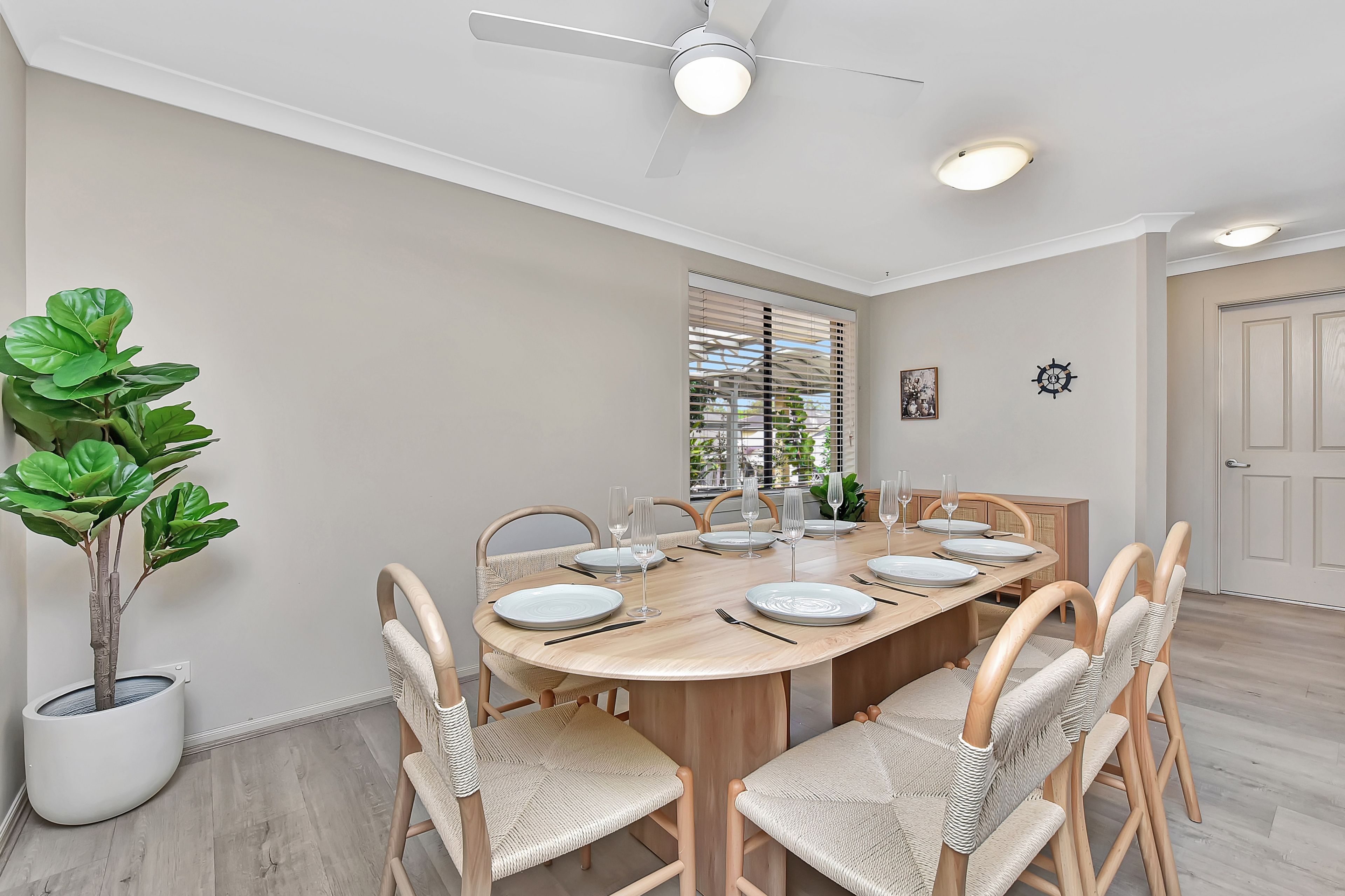 A dining area with a round table, chairs, and a ceiling fan.