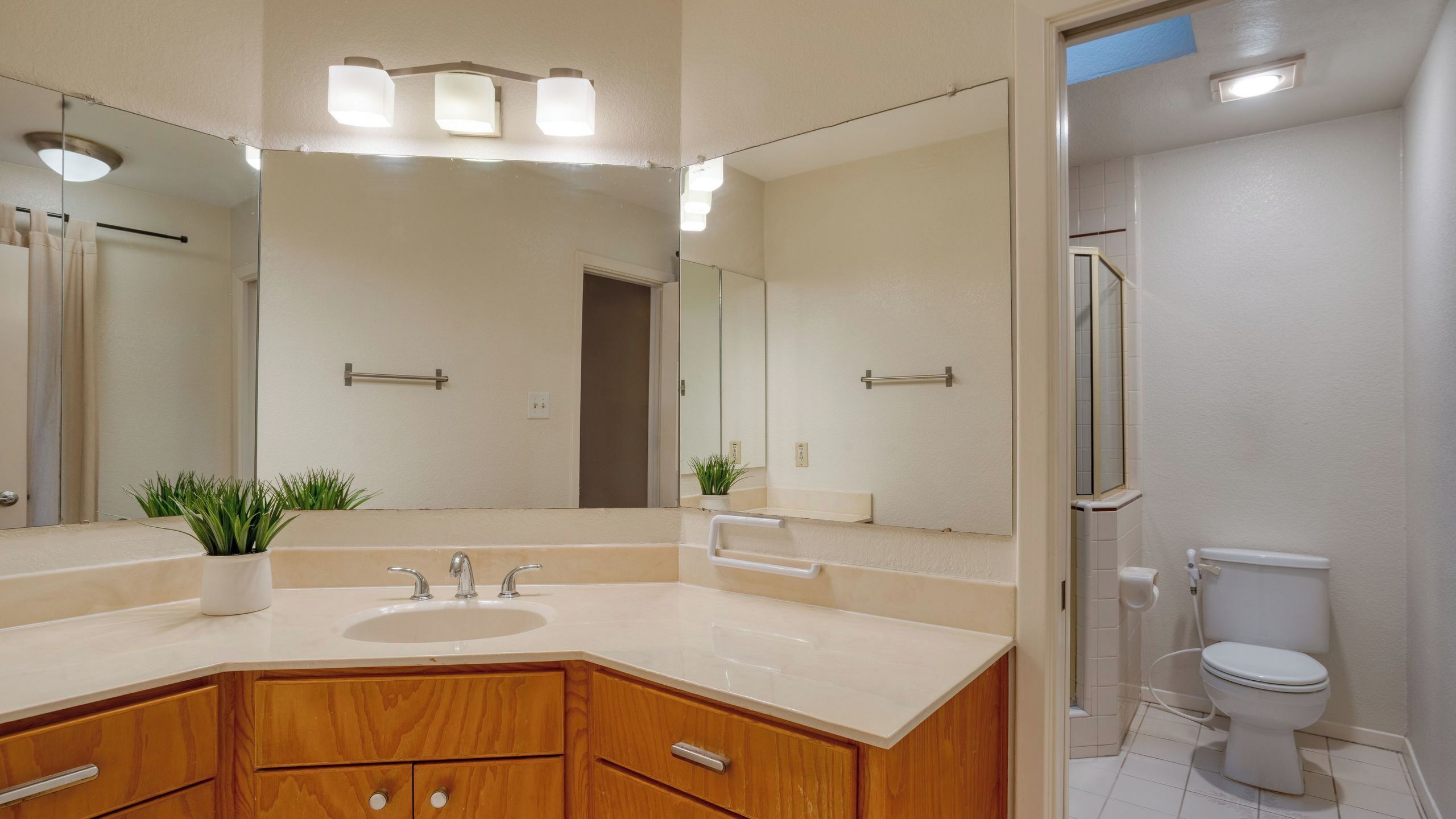 A modern bathroom with a large mirror, a sink, a toilet, and a shower area.