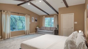 Une chambre avec un grand lit, un canapé et une fenêtre avec des rideaux.