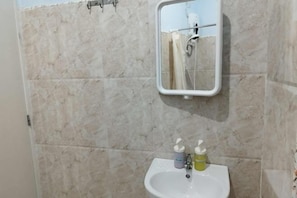Un baño con lavamanos blanco, un espejo y un perchero para toallas.